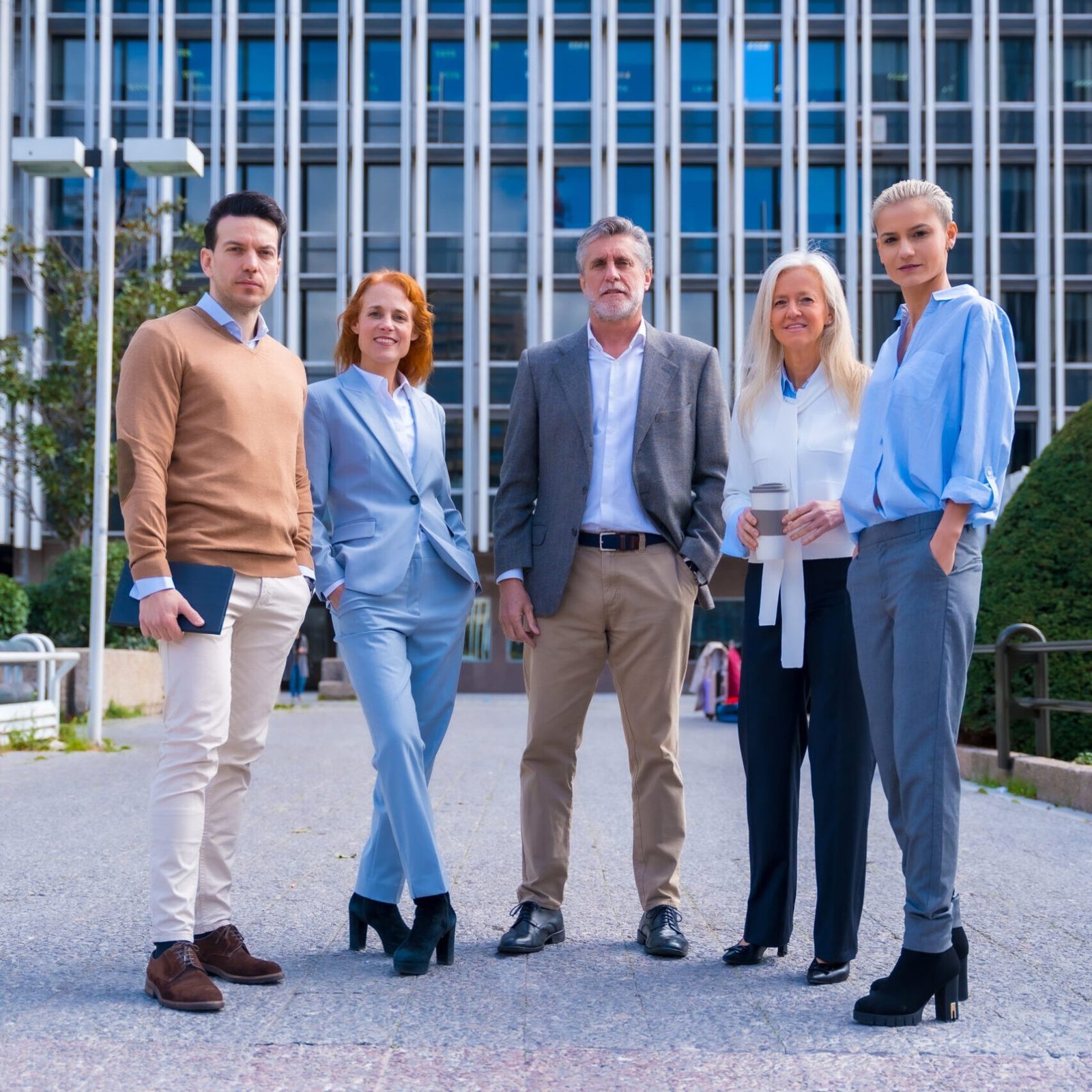 Portrait of cheerful group of coworkers walking outdoors in a corporate office area, Caucasian middle age group